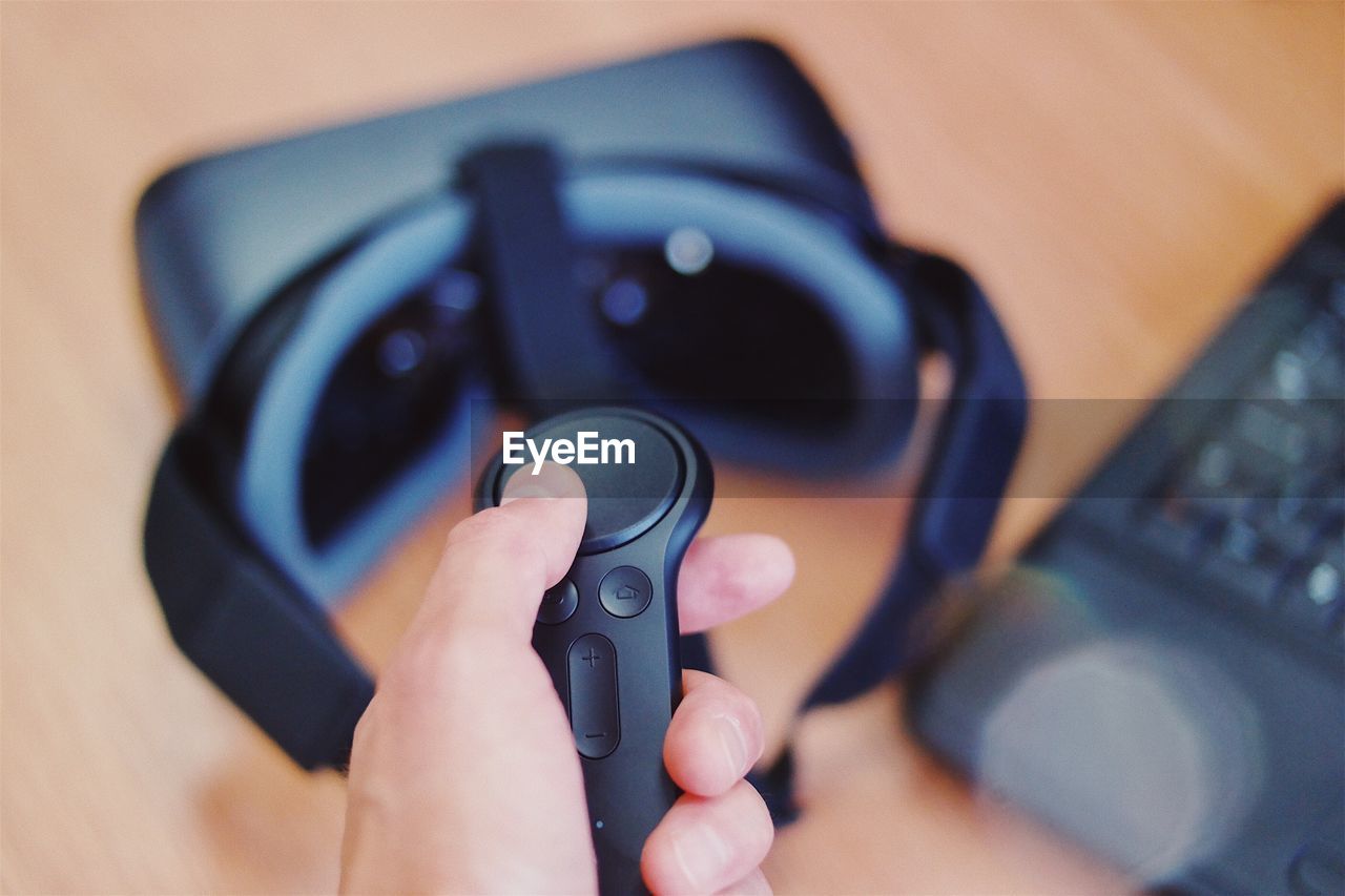 Close-up of hand holding remote control over virtual reality simulator