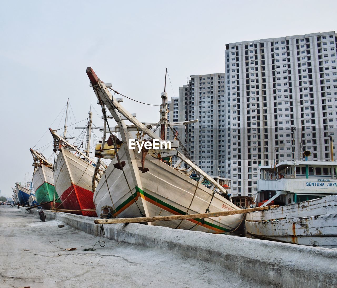 FISHING BOATS MOORED ON SHORE AGAINST BUILDINGS