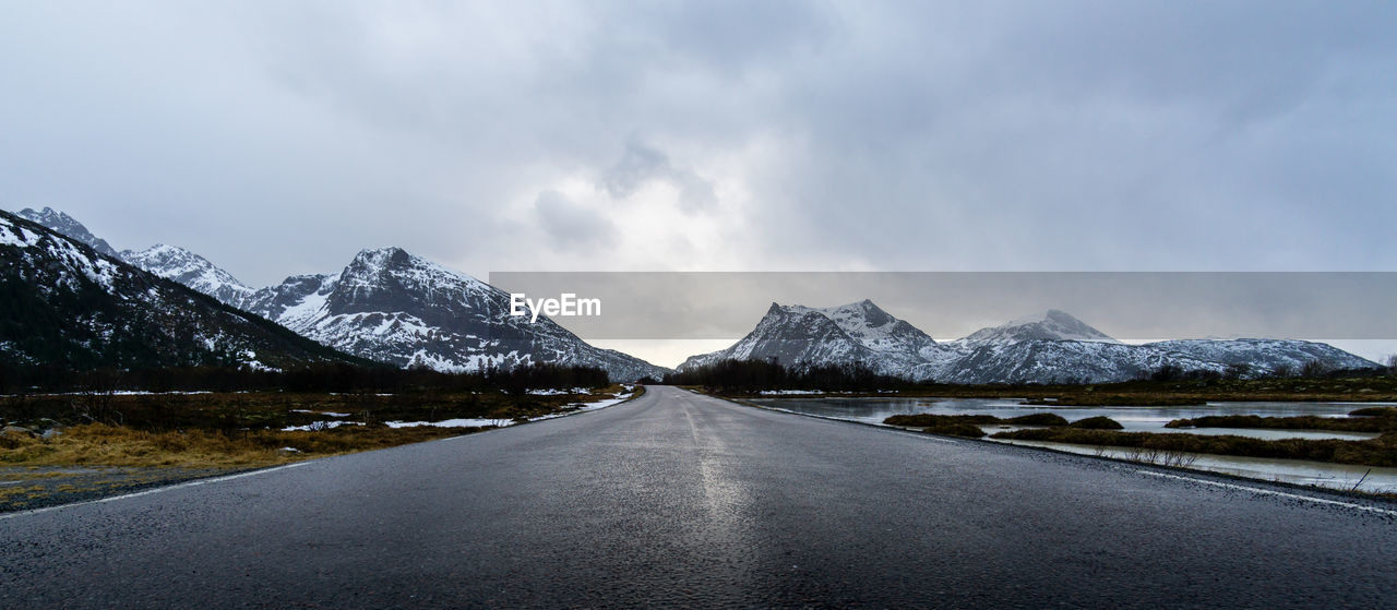 Road amidst snowcapped mountains against sky