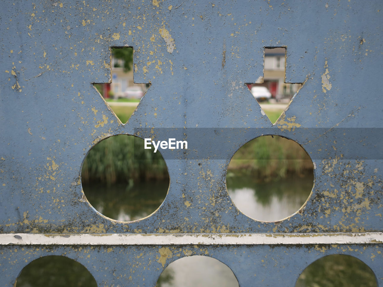 Canal seen through holes and two arrows cut out in a metal plate