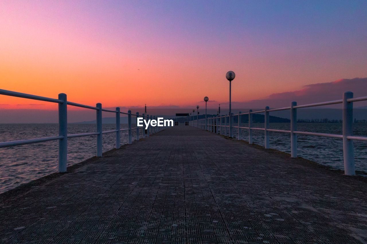 Pier over sea against clear sky during sunset