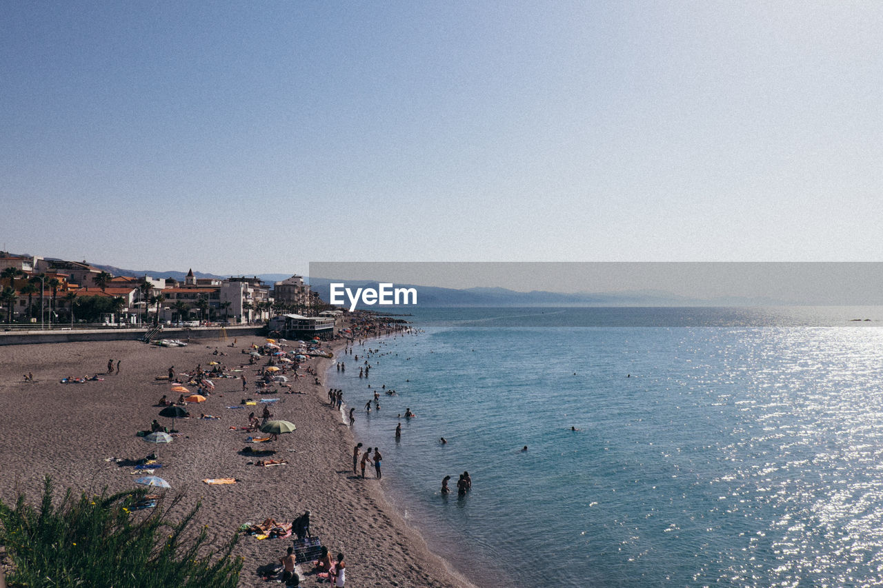 HIGH ANGLE VIEW OF PEOPLE AT BEACH AGAINST CLEAR SKY