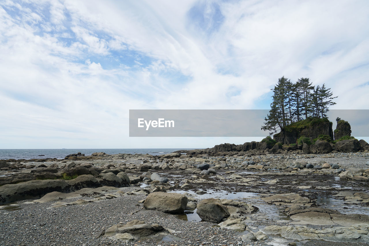 Rocks on shore by sea against sky