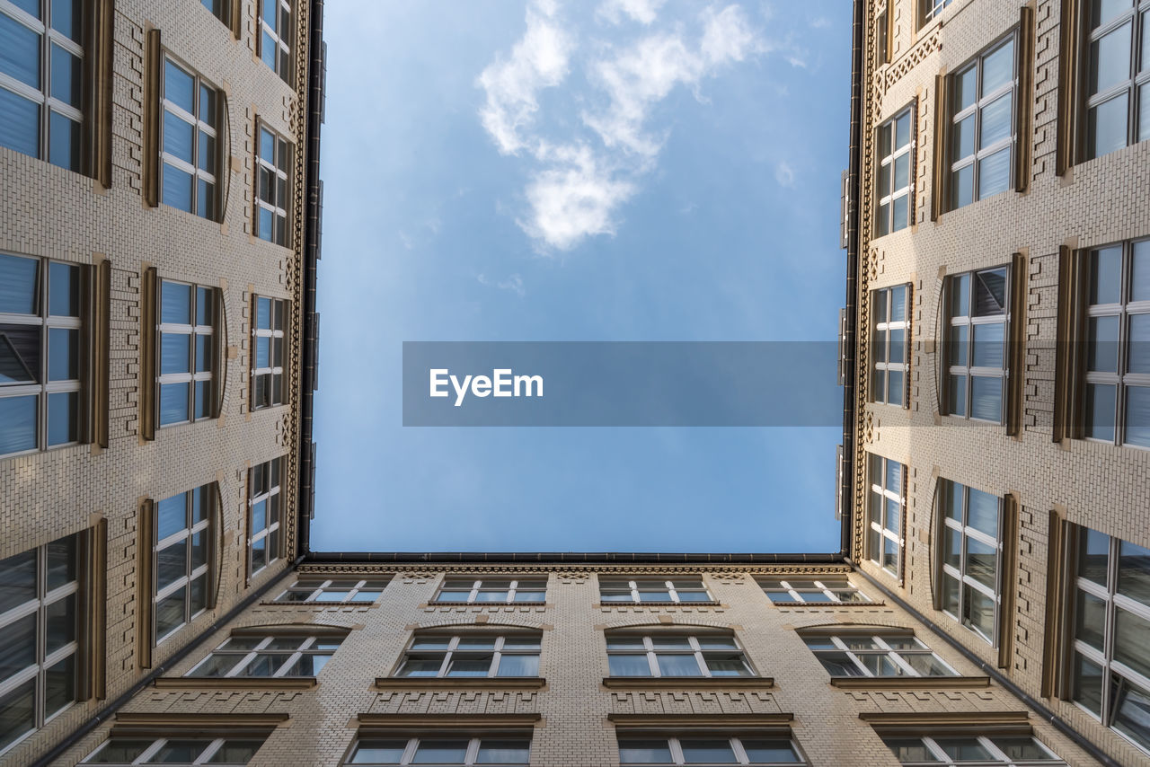 A look up at a white cloud from a courtyard of an old building