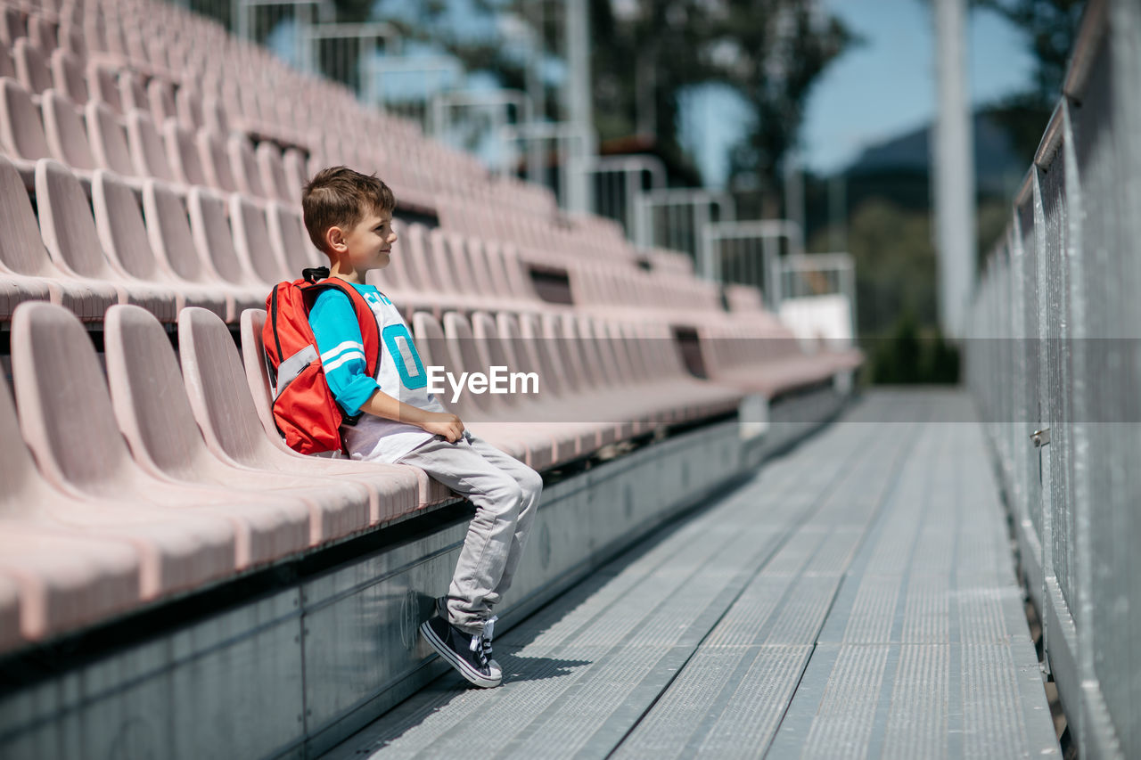 Boy sitting on chair at stadium