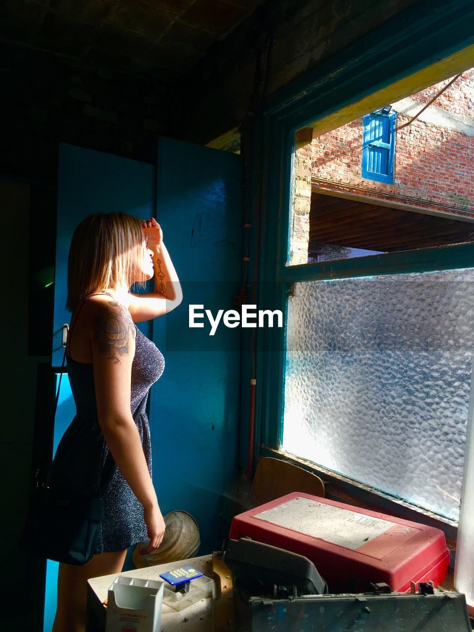 Side view of young woman looking through window
