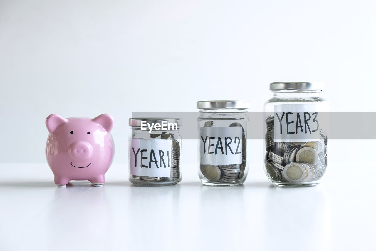 Jars with coins and text on white background