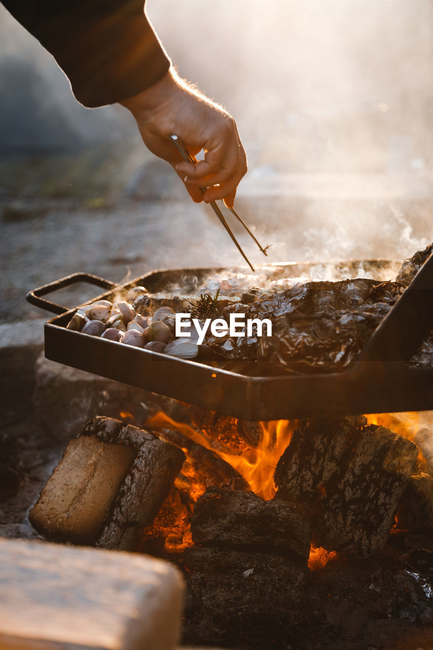 Close-up of person preparing food on barbecue grill