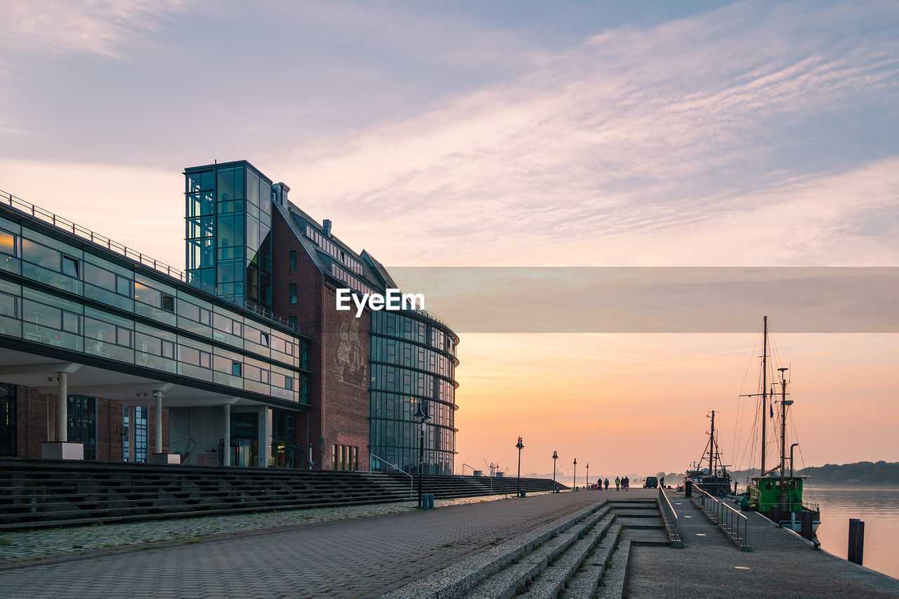 Footpath amidst buildings against sky during sunset