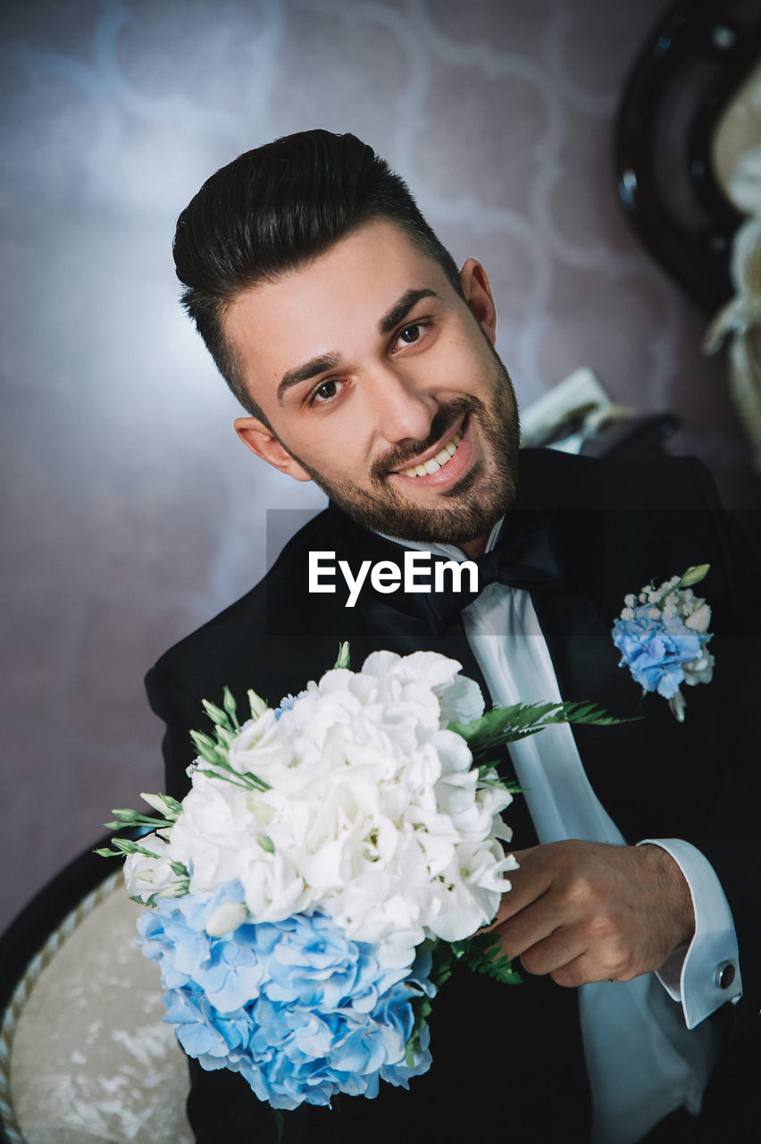 Portrait of confident bridegroom with bouquet