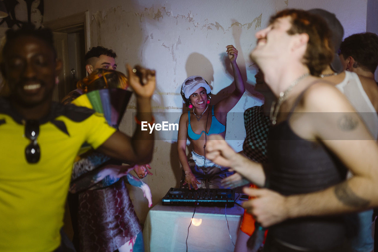 Happy non-binary dj partying with friends at nightclub