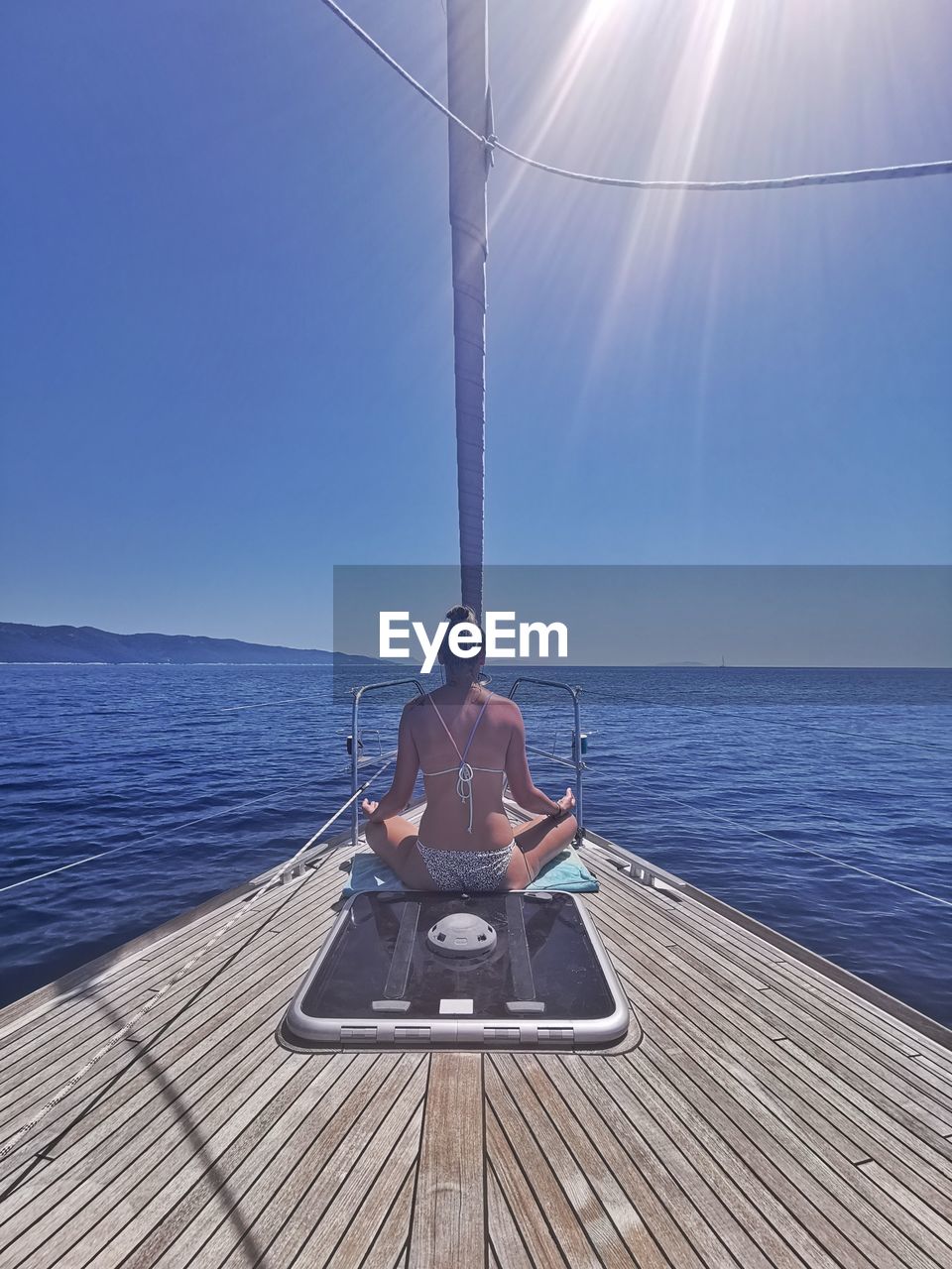 WOMAN SITTING ON SEA AGAINST SKY