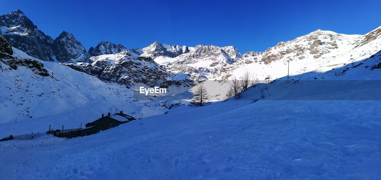 Scenic view of snowcapped mountains against clear blue sky