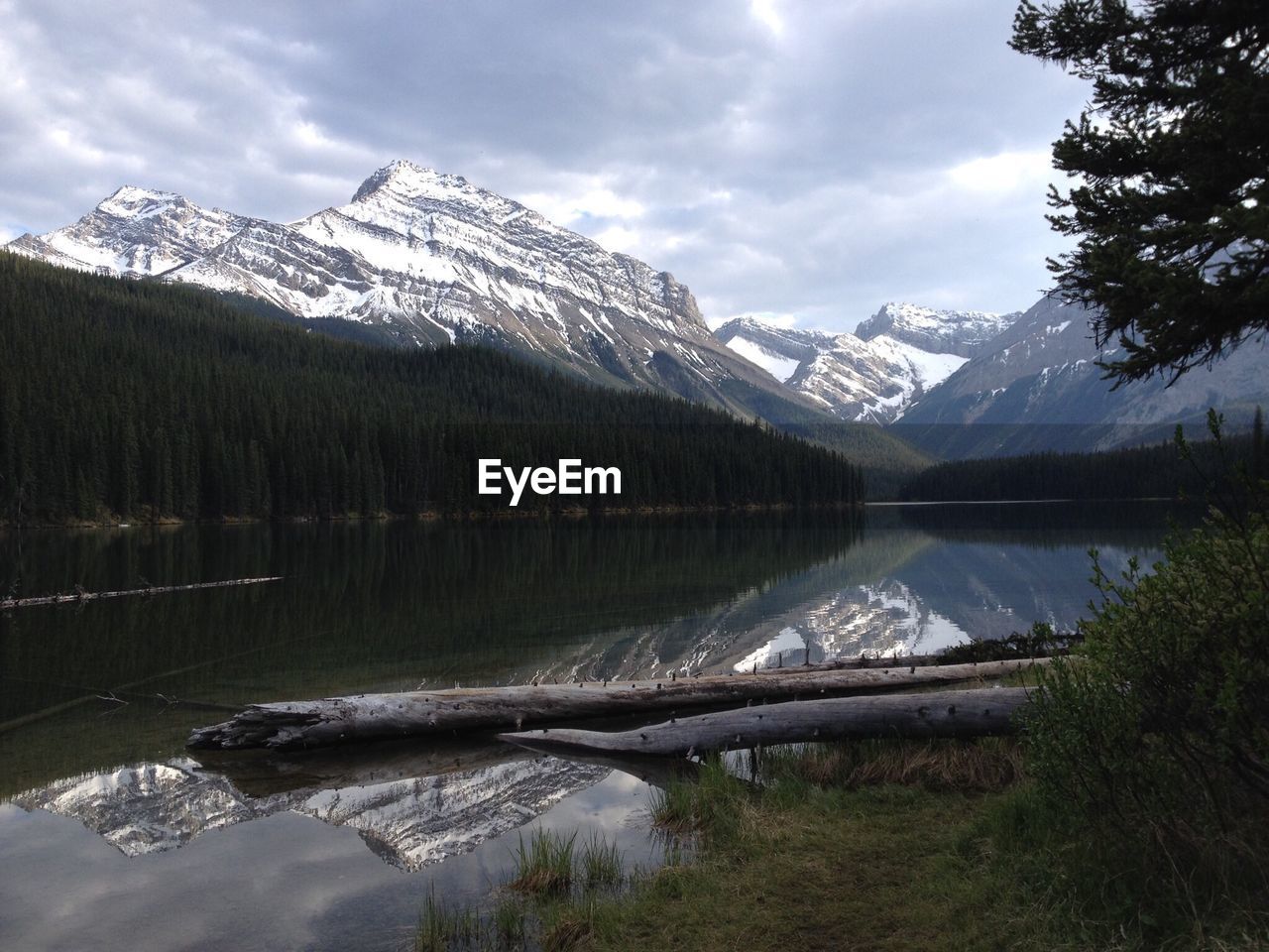 Scenic view of snow covered mountain and lake against cloudy sky