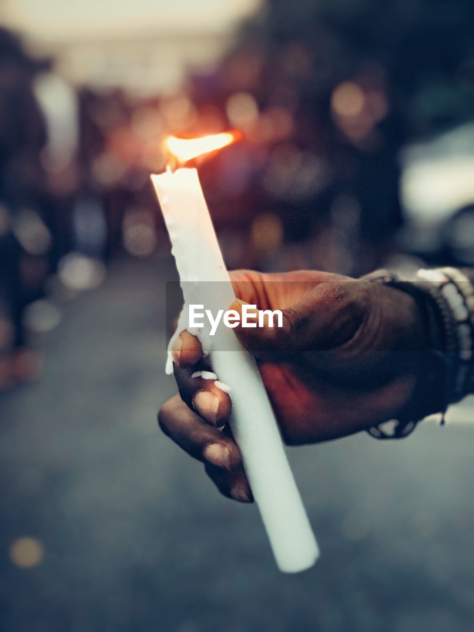 Close-up of hand holding burning candle outdoors