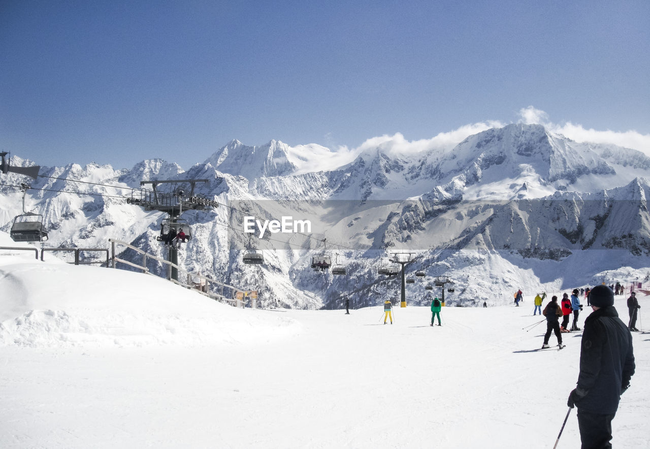 People on snowcapped mountain against clear sky