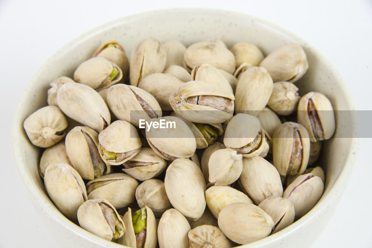 Close-up of pistachio in bowl on white background