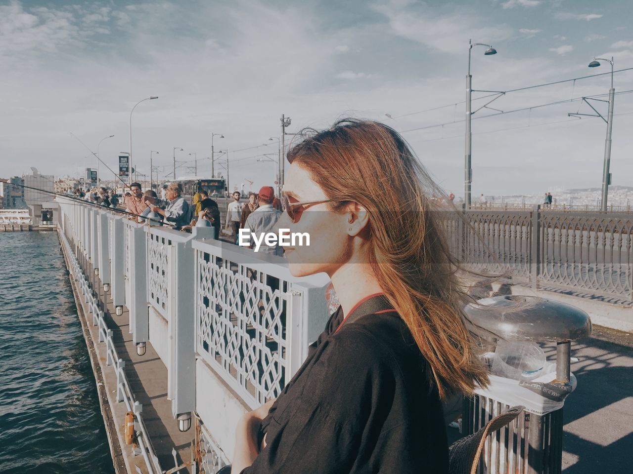 Side view of woman against railing and sky