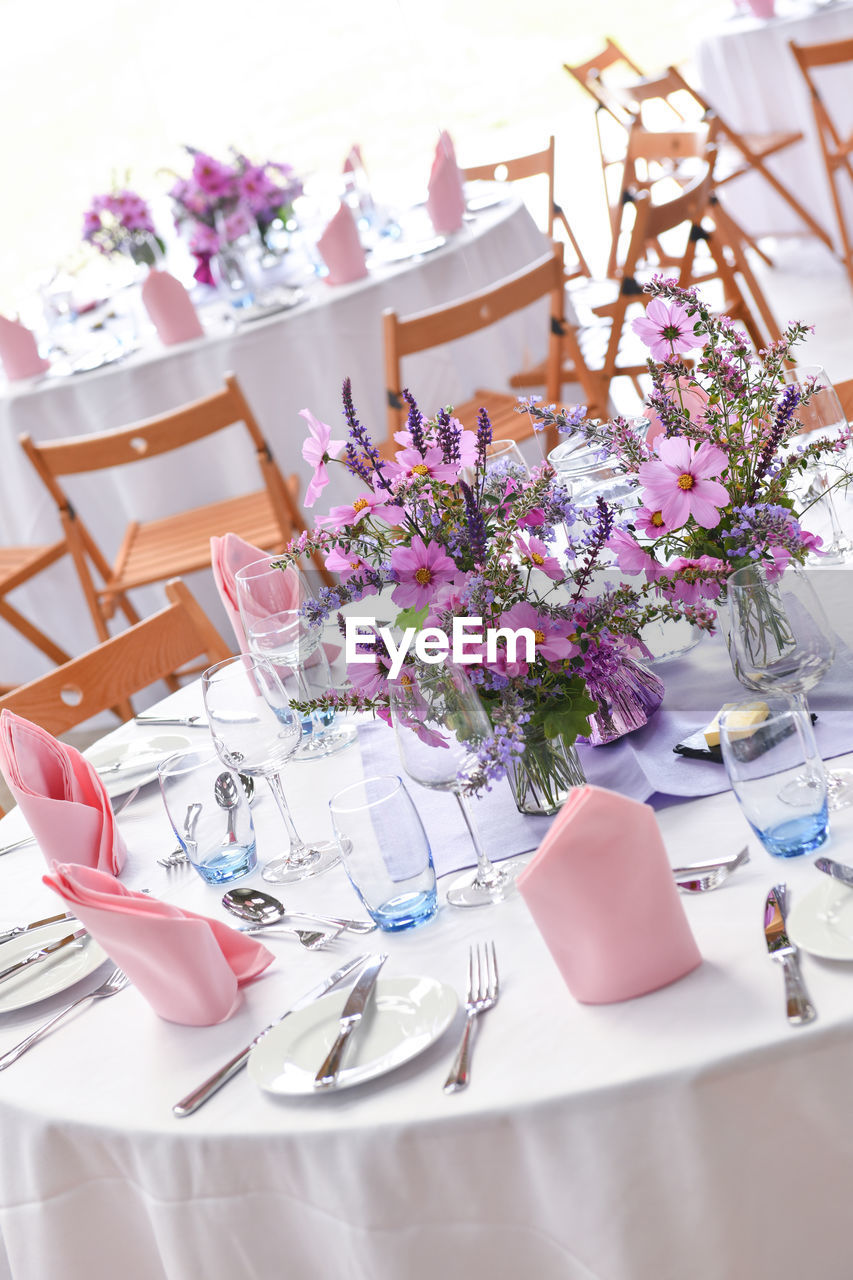 Wide view of table at formal dinner party venue with napkins and glasses