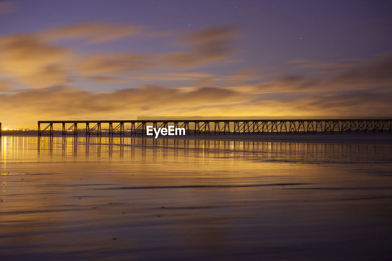 Bridge over sea against sky during sunset