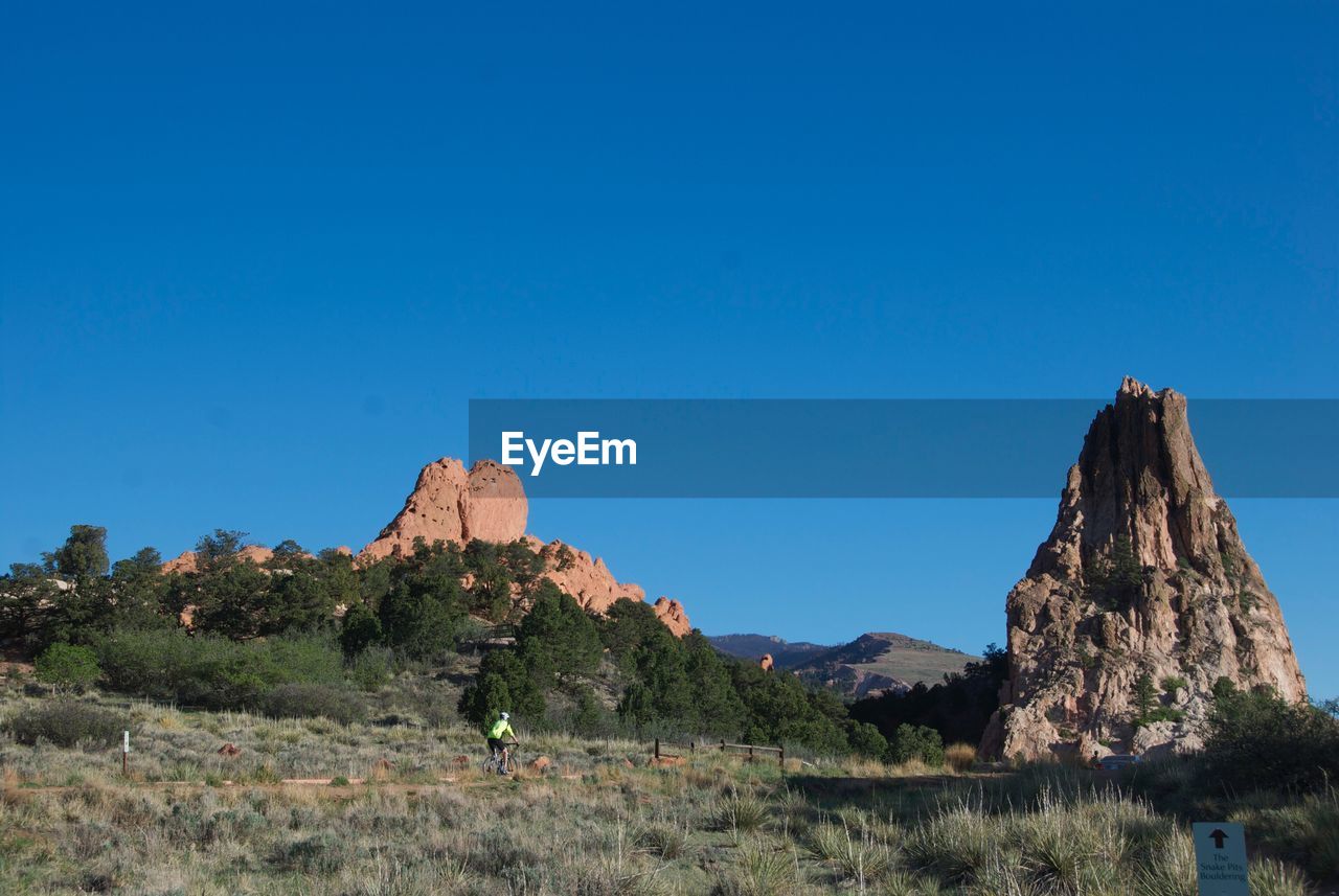 Distant man on bicycle towards majestic rock formations