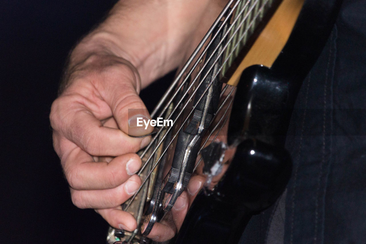 CLOSE-UP OF HAND HOLDING GUITAR