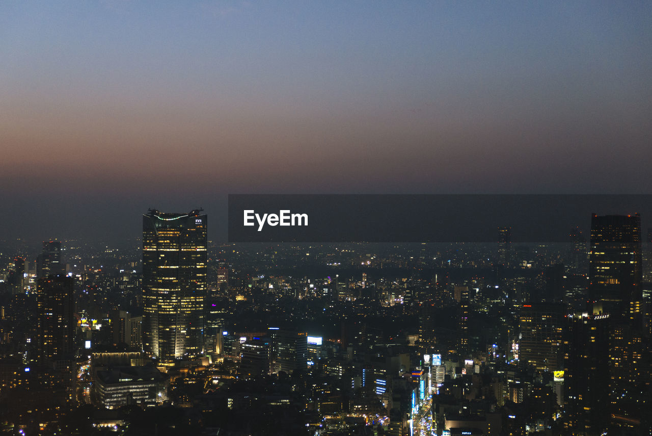 AERIAL VIEW OF ILLUMINATED CITYSCAPE AGAINST SKY