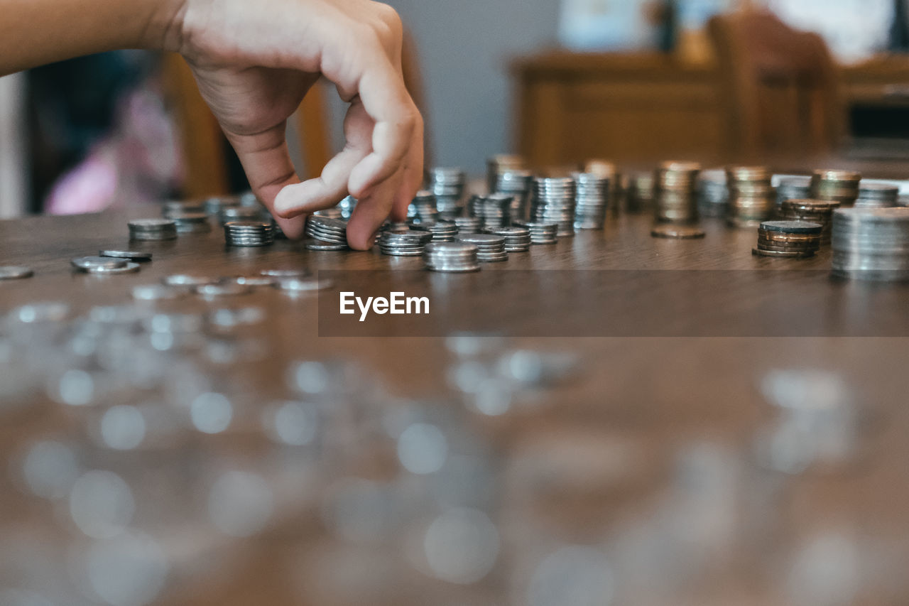 Cropped hand of person stacking coins on table