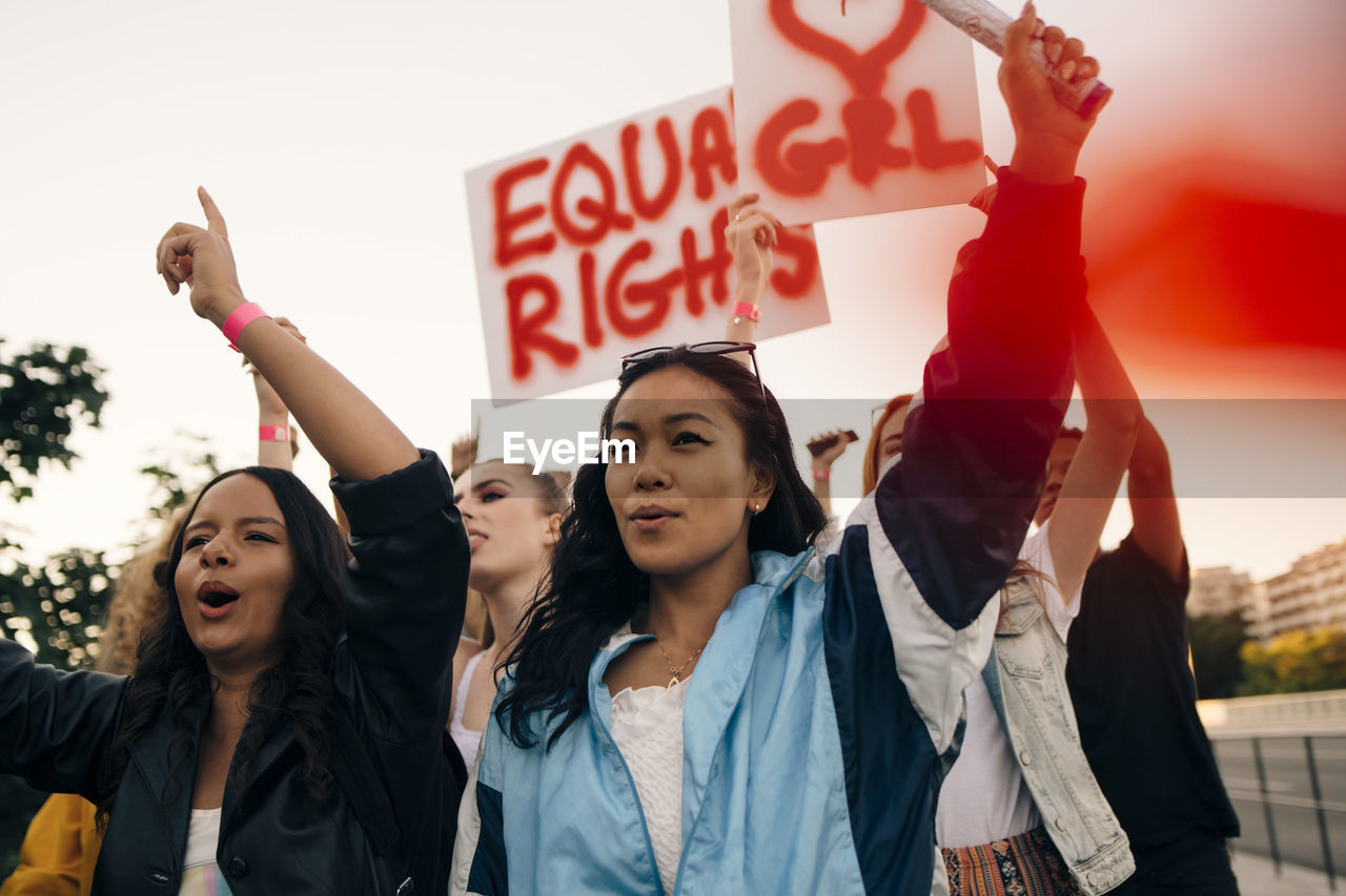 Women with banners protesting together for equal rights against sky