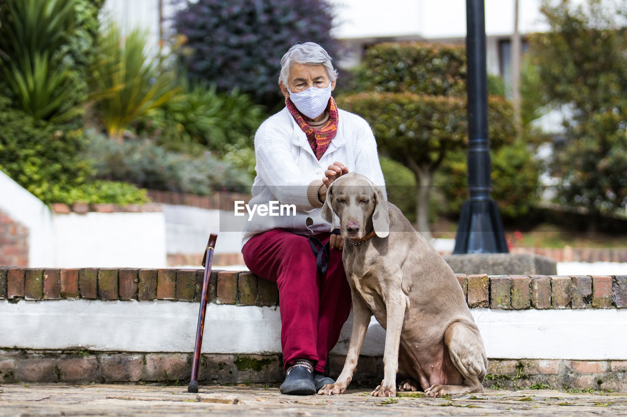 PORTRAIT OF MAN WITH DOG SITTING ON WALL