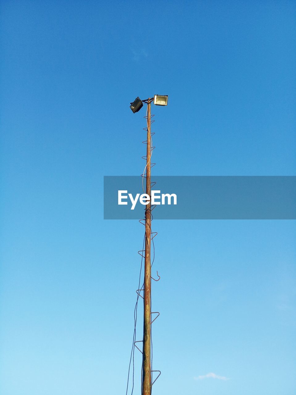 Low angle view of telephone pole against clear blue sky