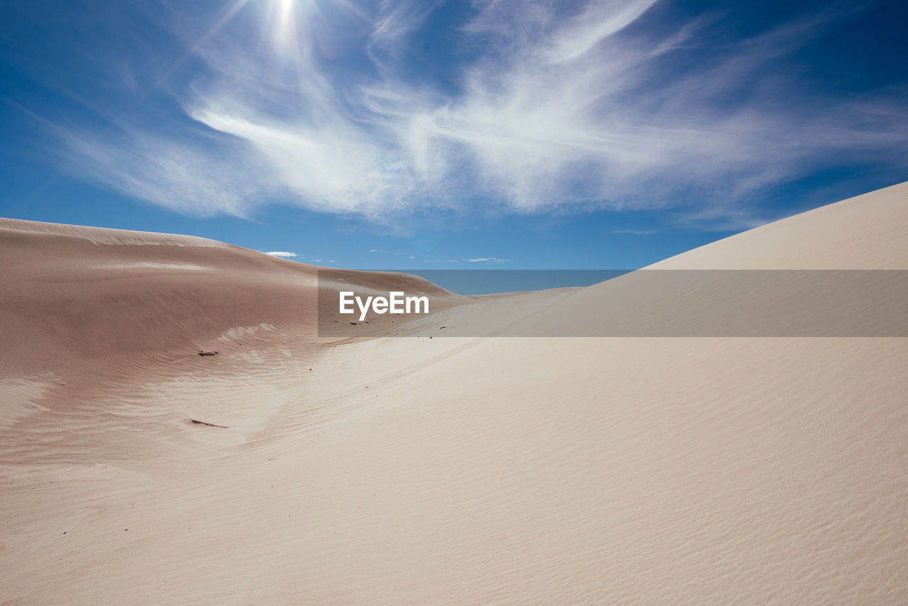 Sand dunes in desert against sky