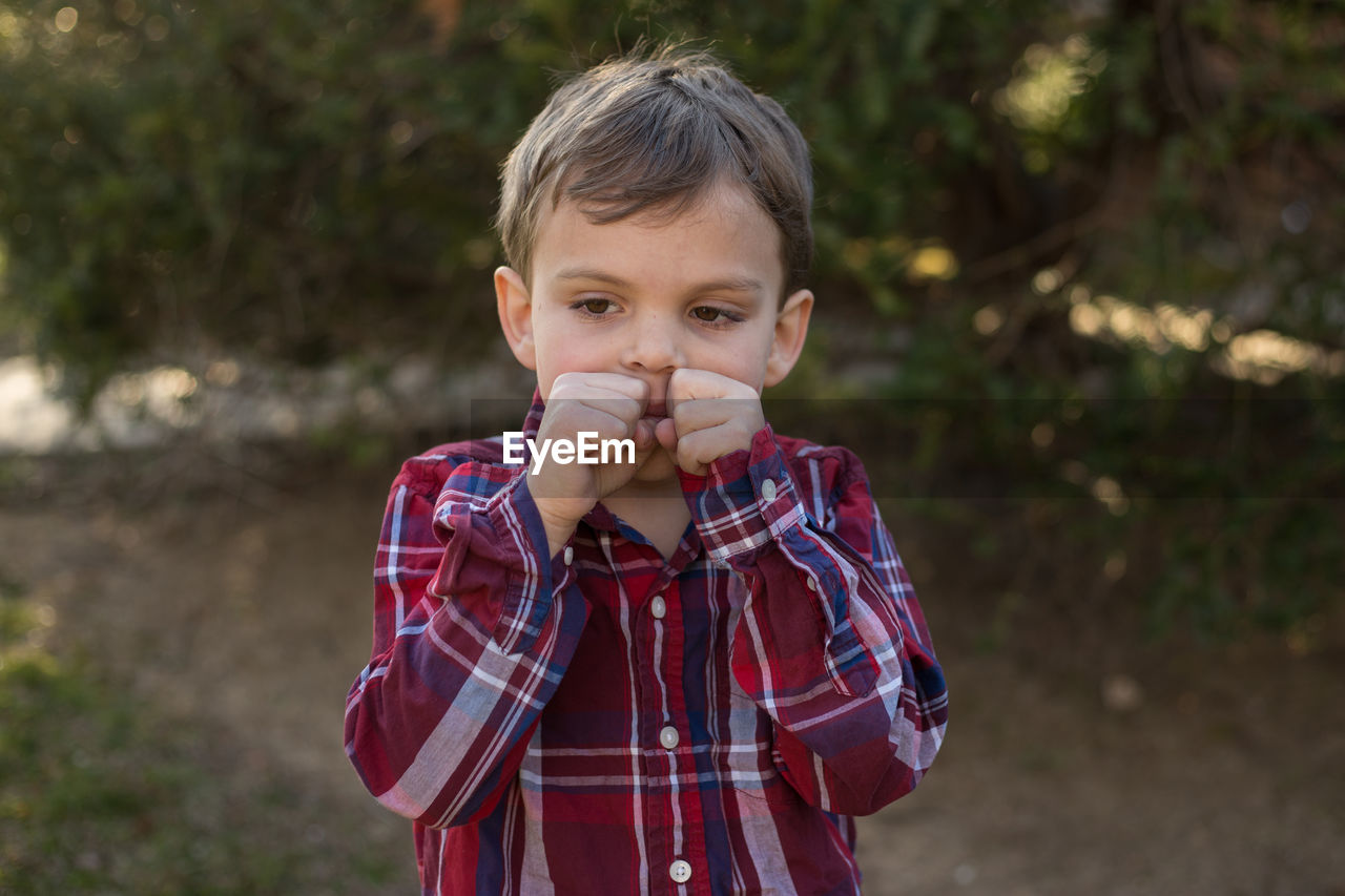 Cute boy looking away while standing outdoors