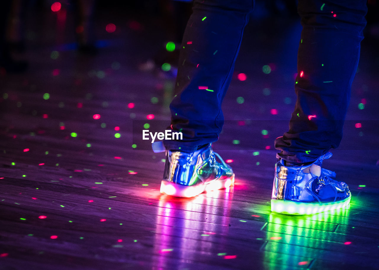 Low section of man wearing illuminated shoes on dance floor
