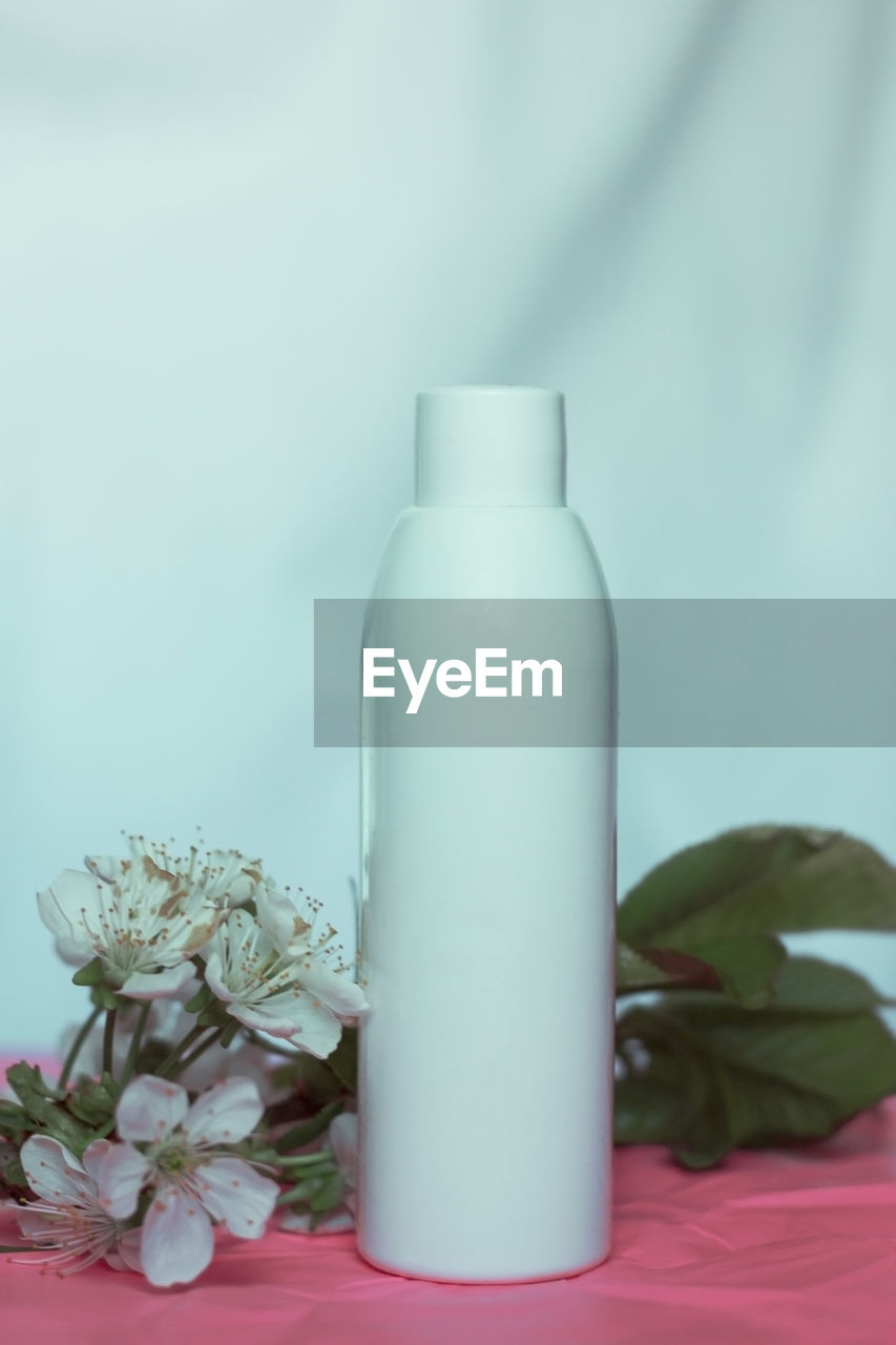 Cosmetic bottle for mockup packaging of skincare product. cosmetic composition with tender flowers