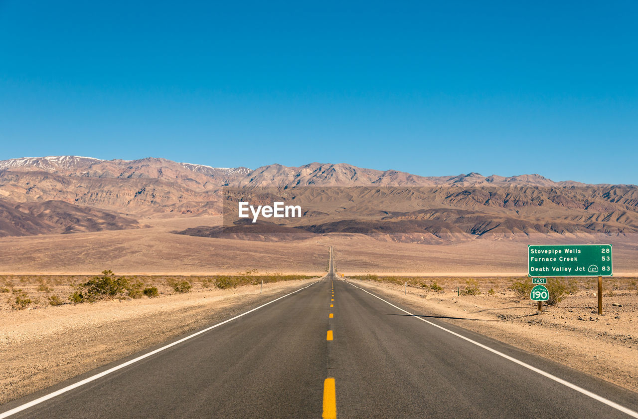 ROAD SIGN AGAINST MOUNTAIN RANGE