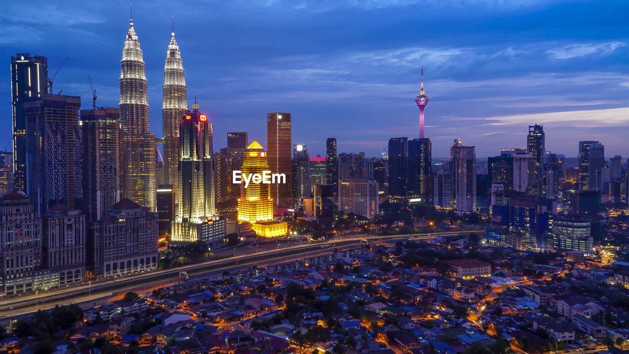 Illuminated city buildings against sky