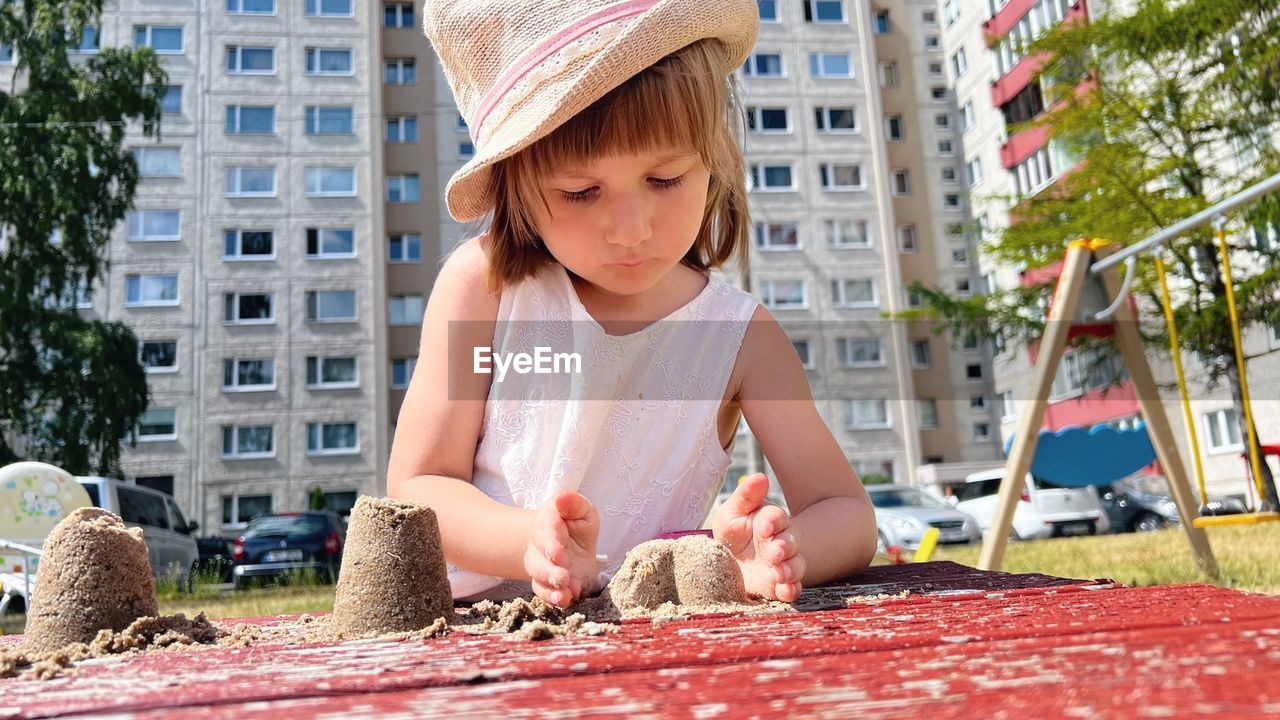 Small girl playing at playground at backyard of blocks of flats
