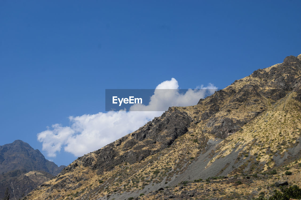 Low angle view of mountain against blue sky