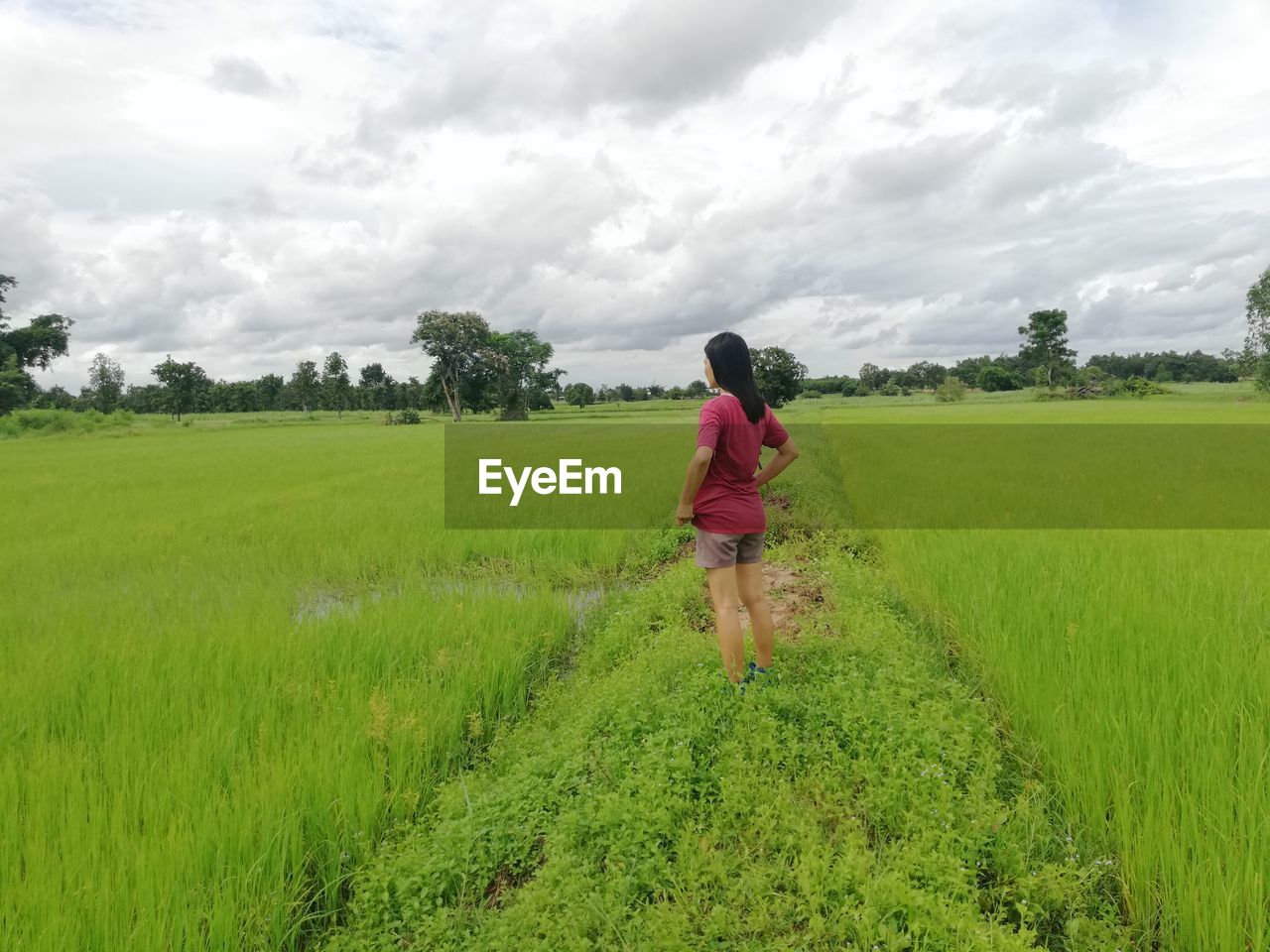 Woman standing on field against cloudy sky