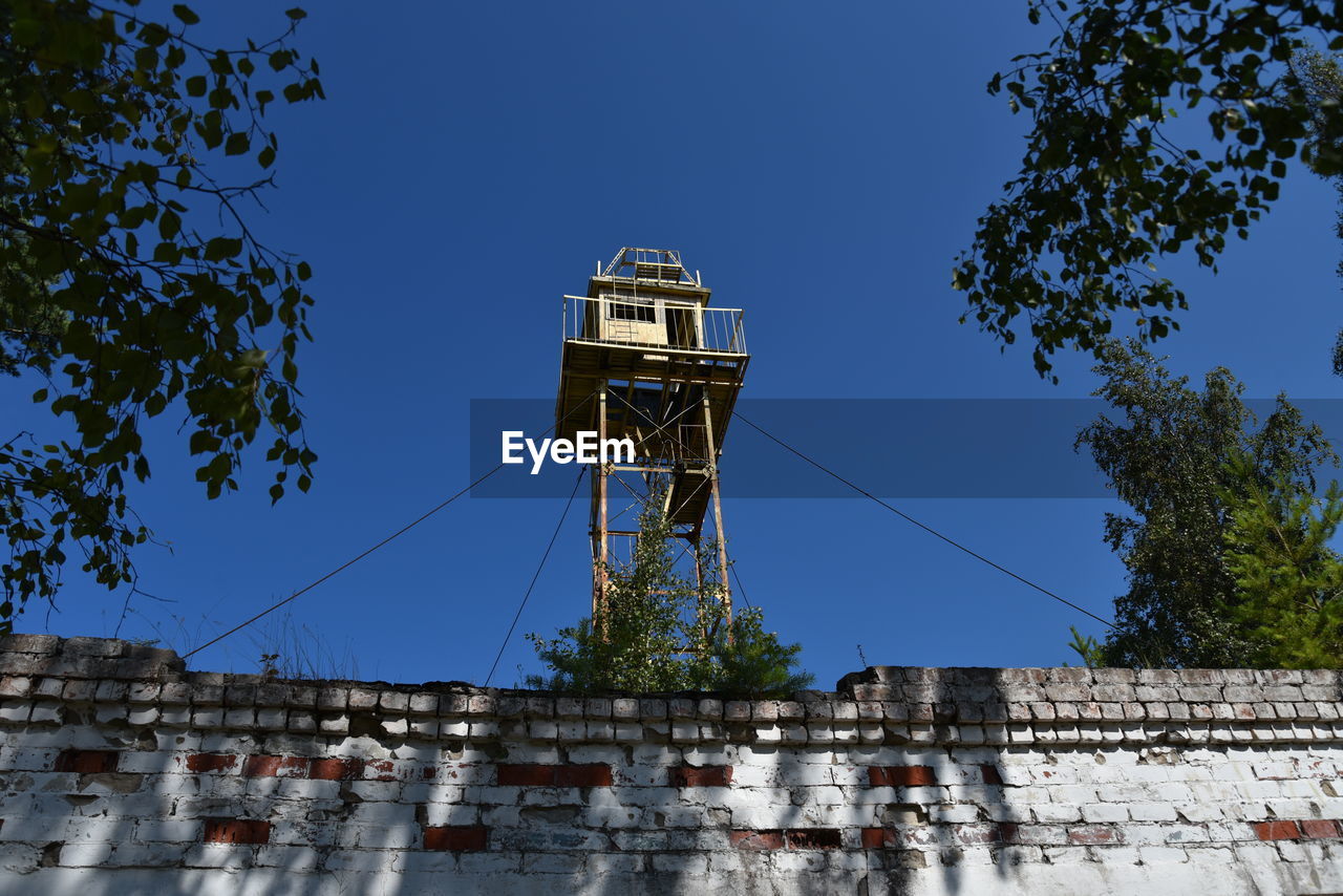 Low angle view of water tower against clear blue sky