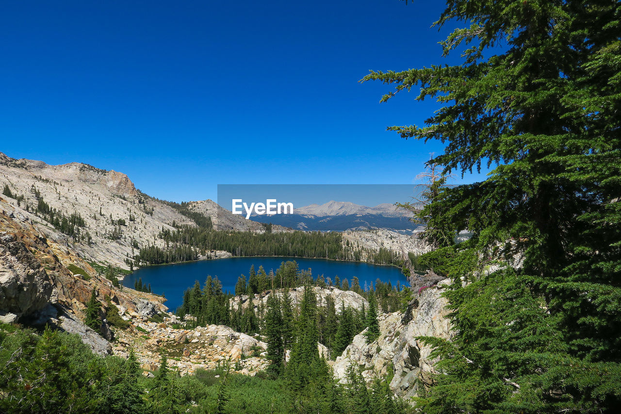 Scenic view of river and mountains against clear blue sky