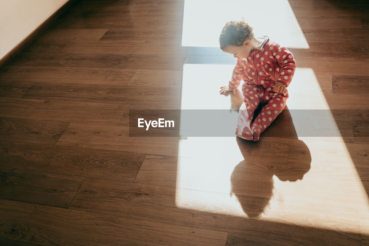 High angle view of cute girl sitting on floor at home