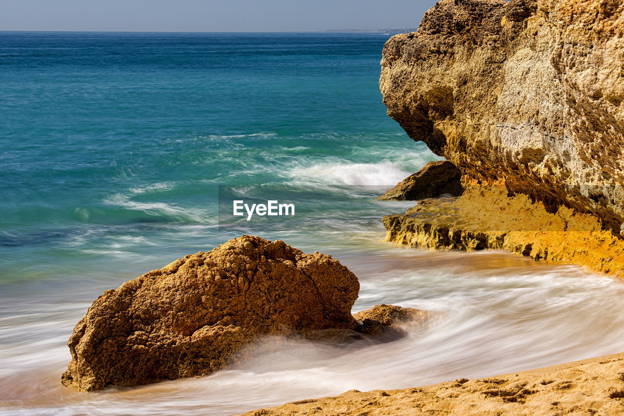 Rock formation on beach against sky