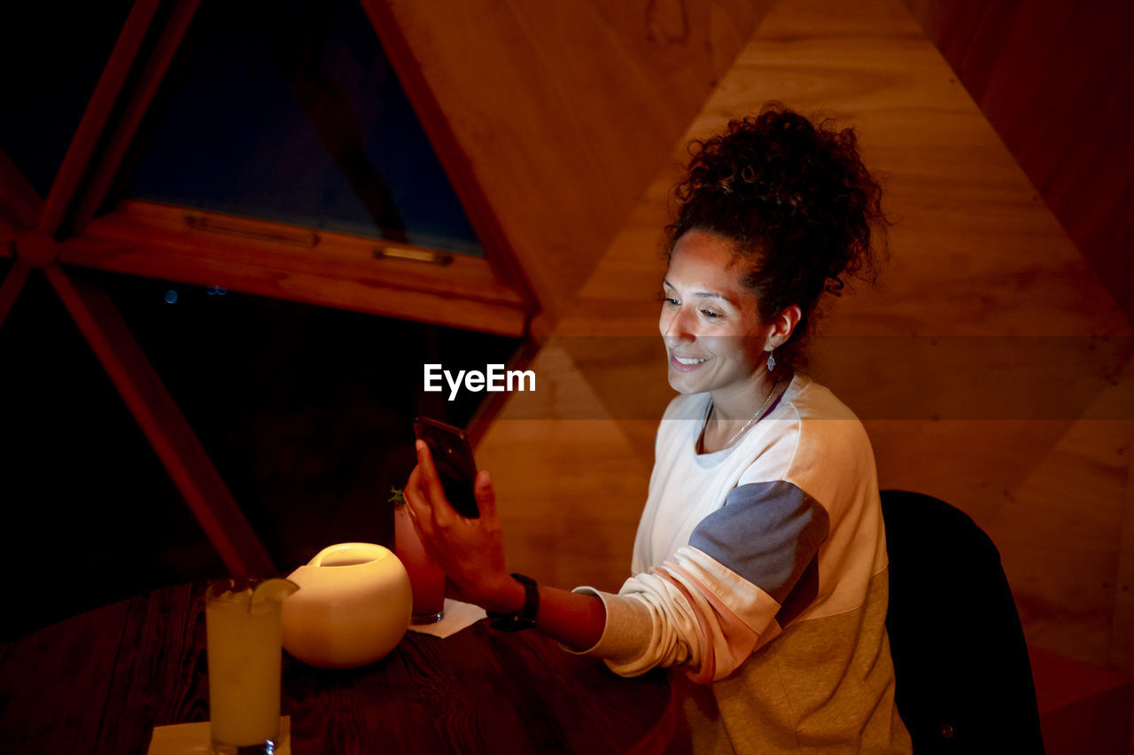 Woman using a mobile phone while relaxing in a dome tent.