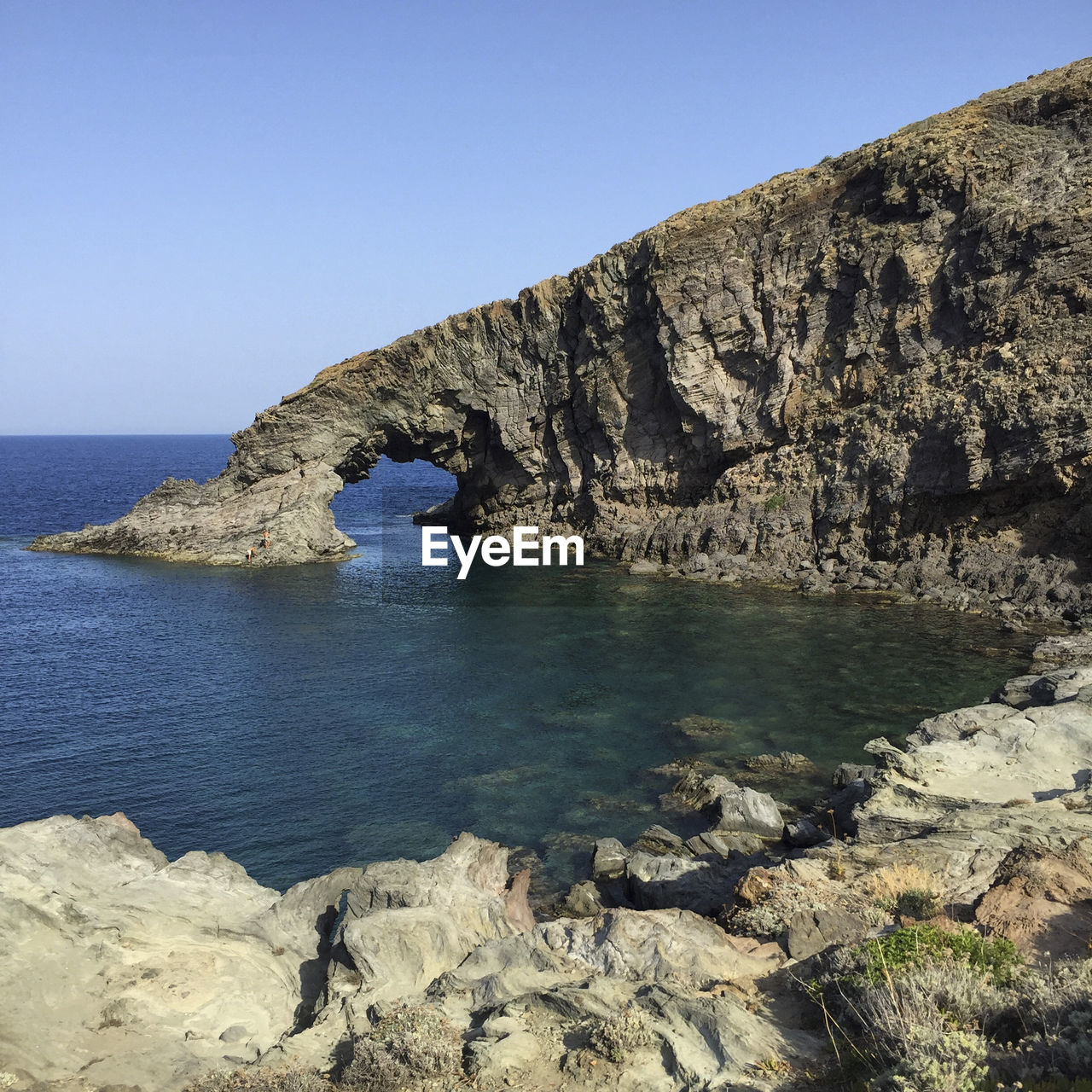 ROCK FORMATIONS BY SEA AGAINST CLEAR SKY