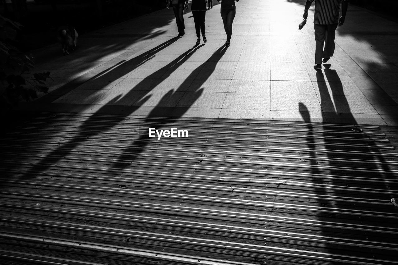 LOW SECTION VIEW OF PEOPLE WALKING ON ROAD