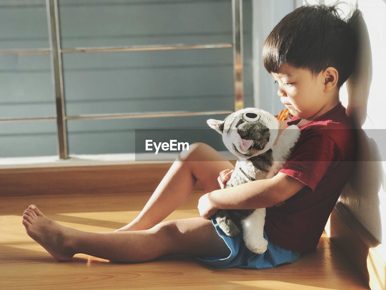 Cute boy sitting with stuffed toy cat at home