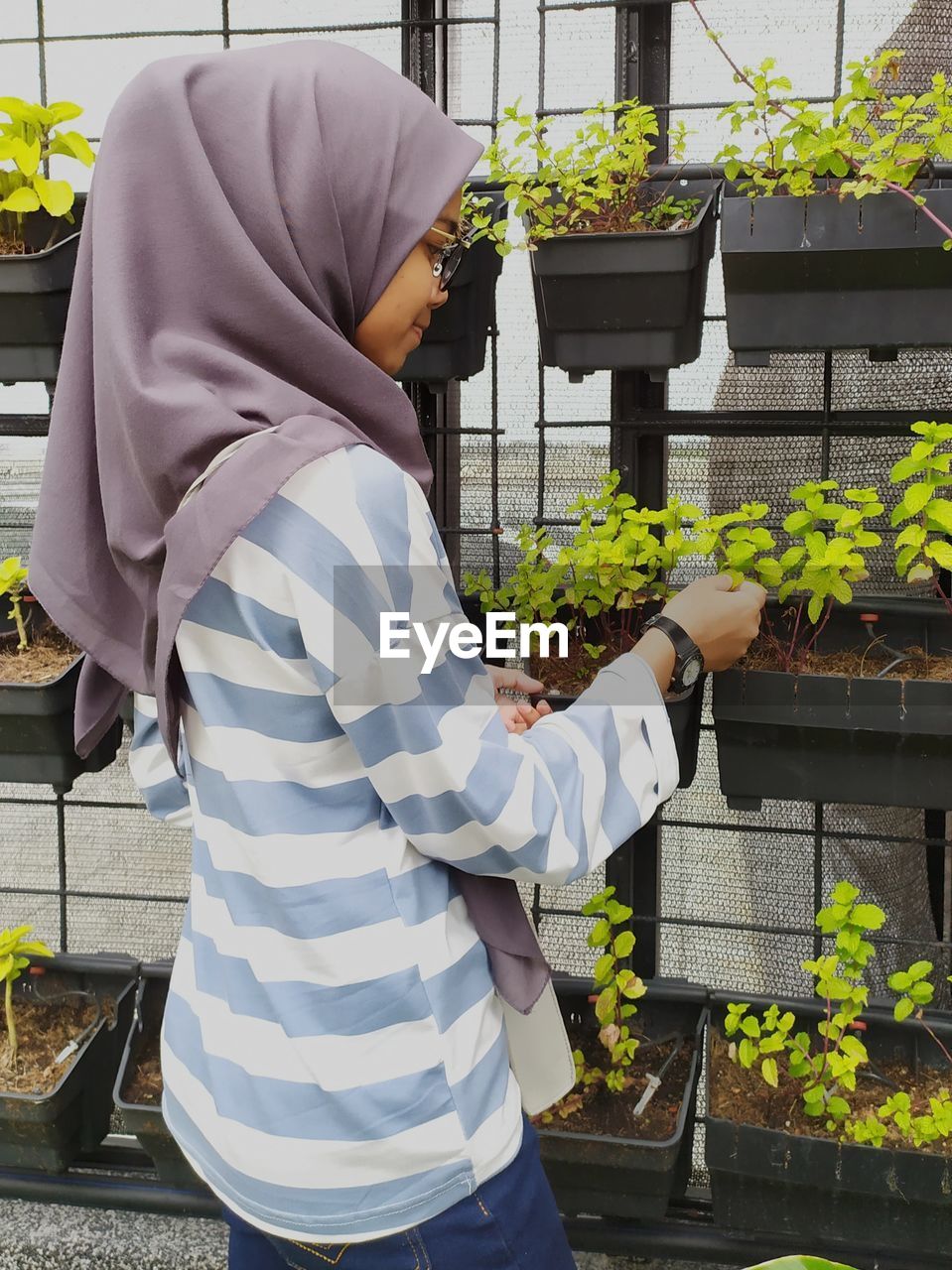 Rear view of woman standing by potted plants