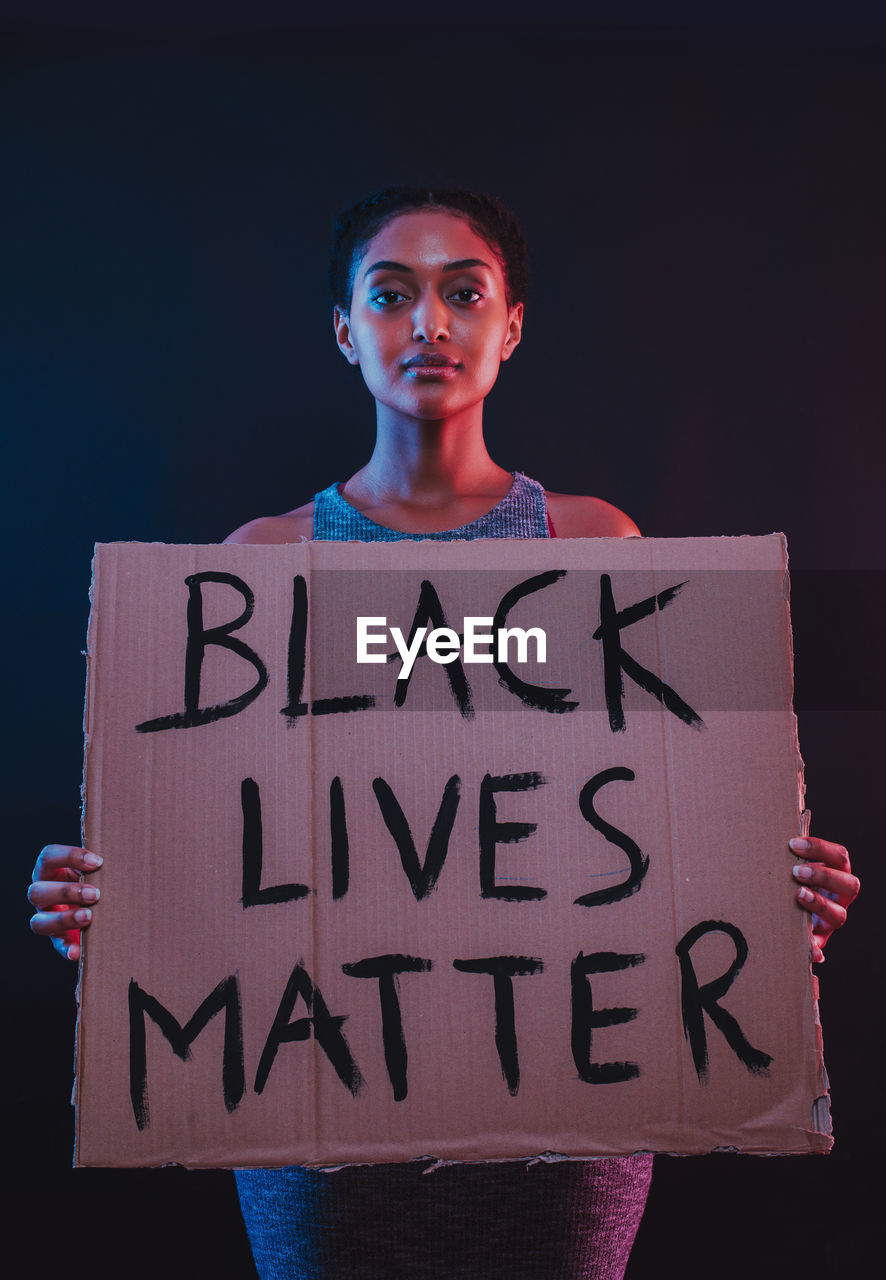 Portrait of teenage girl standing against black background